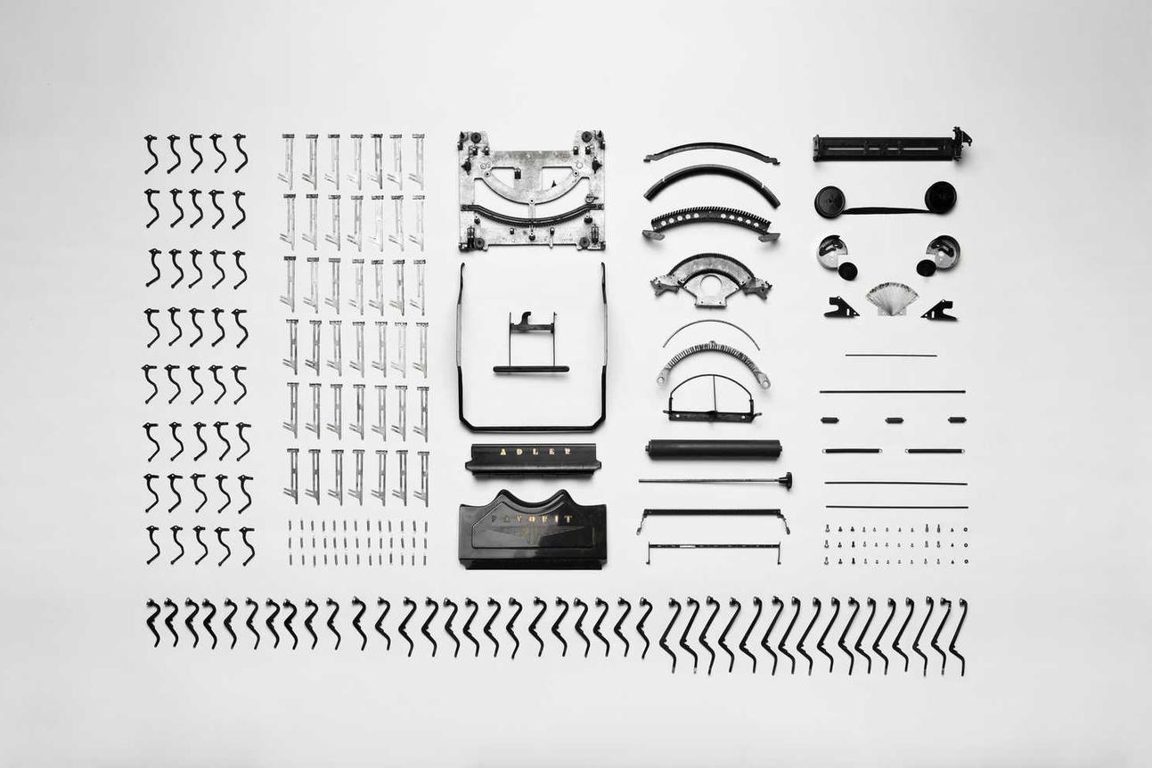 Banner Image. Parts of an antique typewriter laid out methodically on the board.