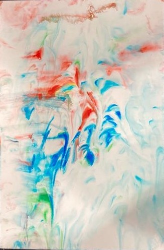 Laid on a black background is a piece of photo paper. On it includes an array of colors swirled together. The colors include blue, red, and green. 