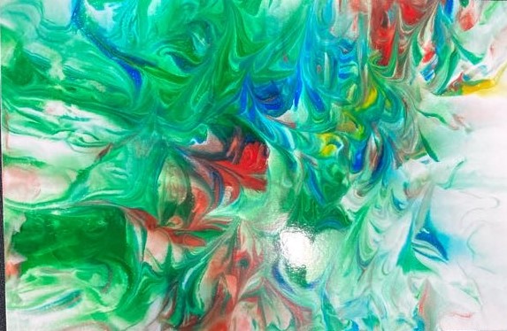 On a black background a colorful piece of photo paper lies. The colors included are green, blue, red, yellow, and white. They are swirled together almost looking like spikes. 