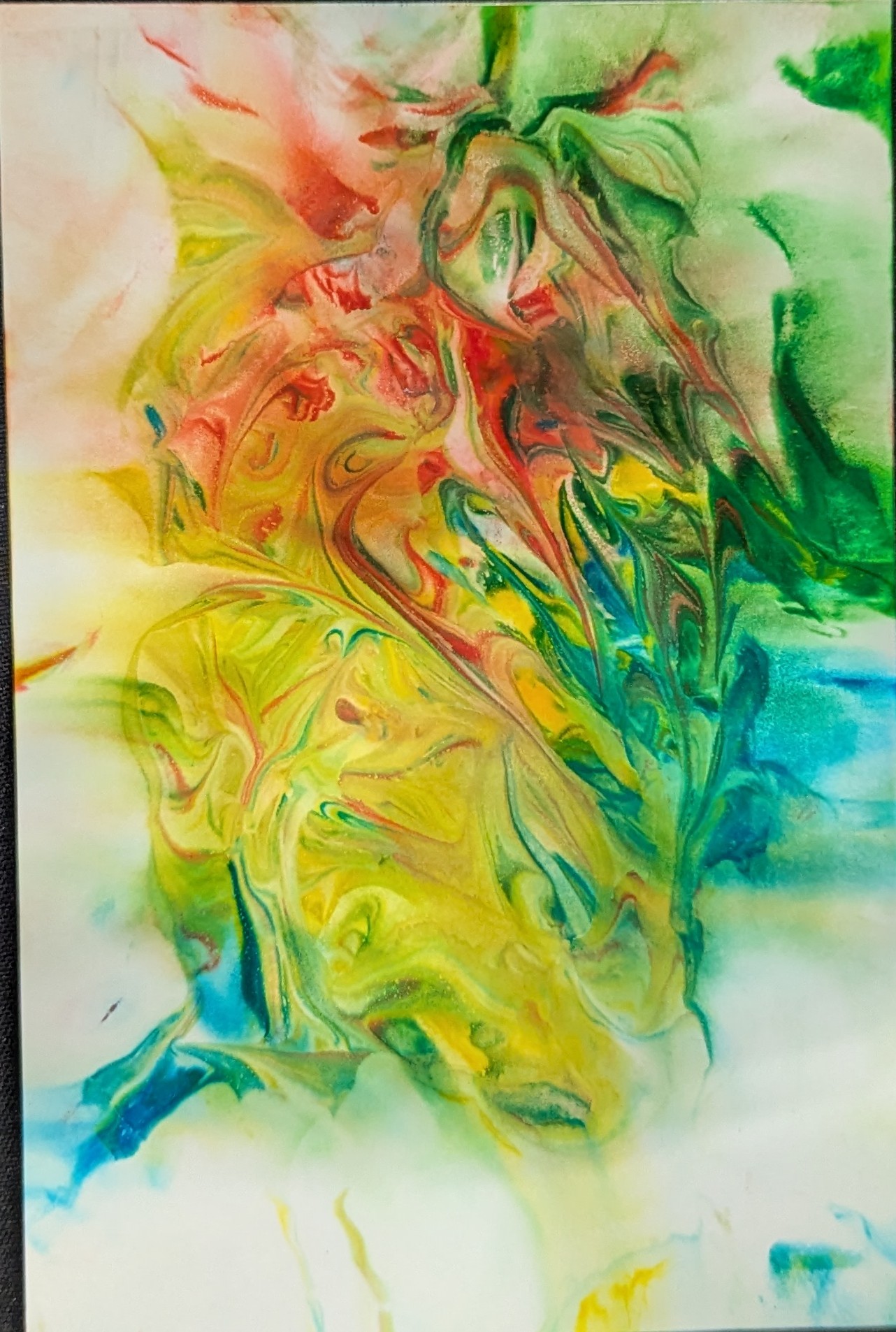  A piece of photo paper lies on a black background. The paper has an assortment of colors mingled together; red, yellow, green, and blue.